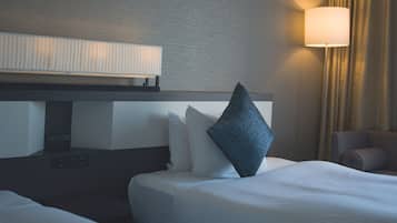 A hotel room with a bed, a control panel, a lamp, and a chair.