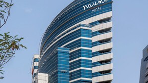Un edificio moderno de hotel con fachada curva, que presenta un cartel llamativo que dice "naum hotel".