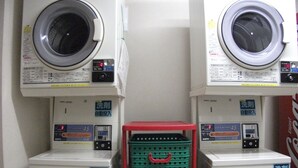 Two front-loading washing machines with control panels, stacked on top of each other, and a red and green basket between them.