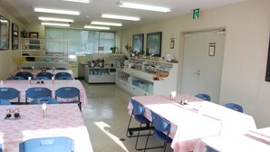 A dining area with tables and chairs, a kitchen area with appliances, and a window with blinds.