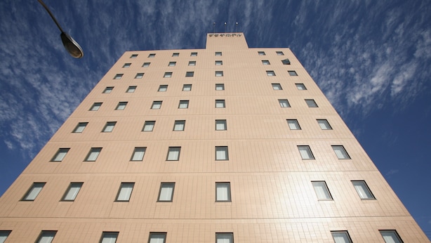 A tall, modern building with a grid of windows and a clear sky.