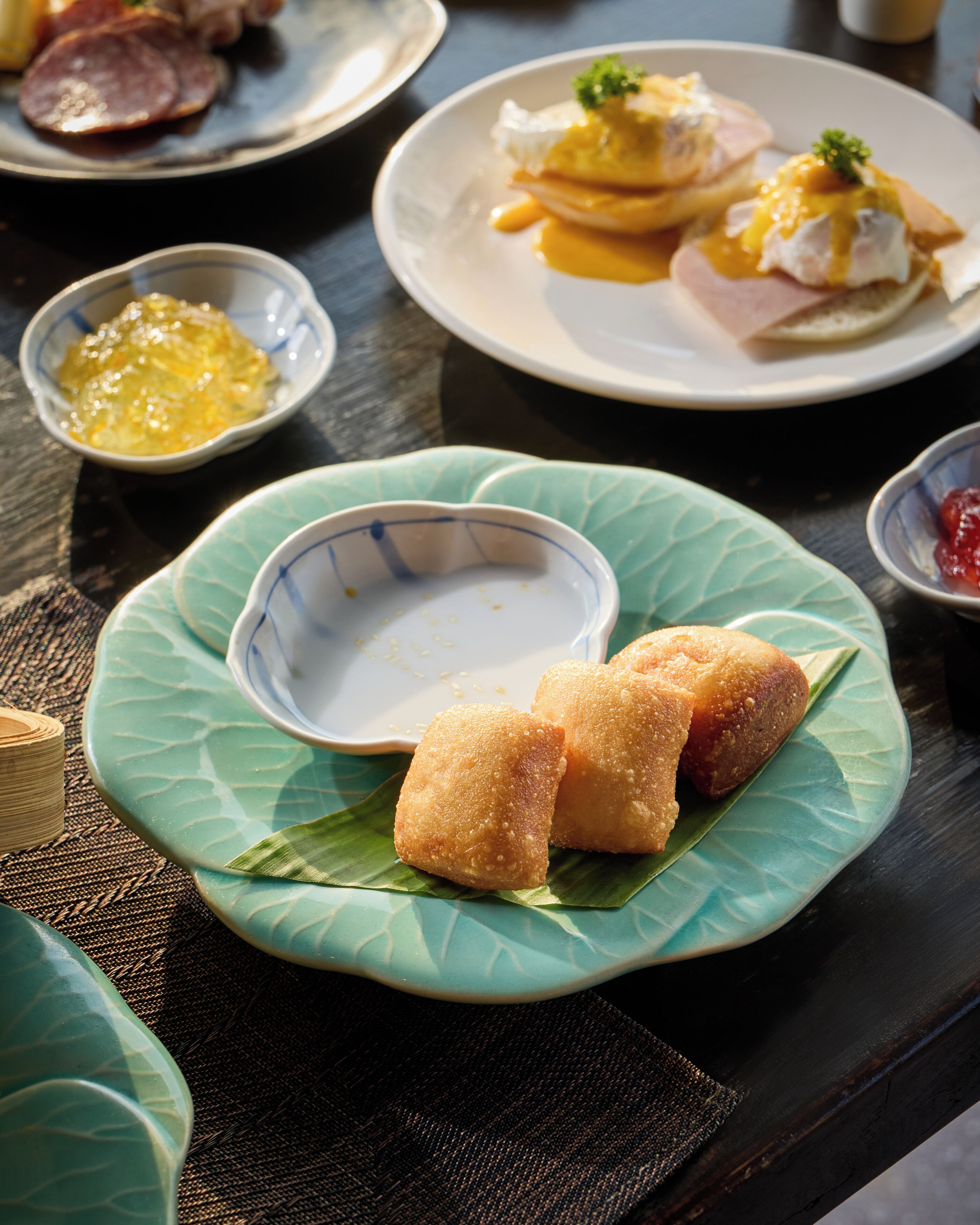 Ein Tisch mit Speisen, darunter ein tellerförmiges, grünes Blatt mit frittierten Speisen und eine kleine Schale Soße.