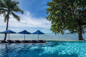 A poolside area with lounge chairs and umbrellas, overlooking a body of water. - Homm Chura Samui (Koh Samui)