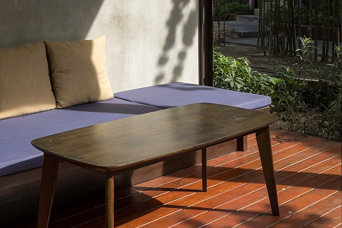 A modern outdoor seating area with a wooden table and a cushioned bench.
