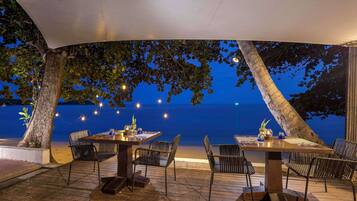 An outdoor dining area with tables and chairs, overlooking a body of water.