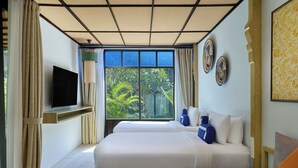 A hotel room with two beds, a TV, a window with a view of greenery, and decorative plates on the wall. - Homm Chura Samui (Koh Samui)
