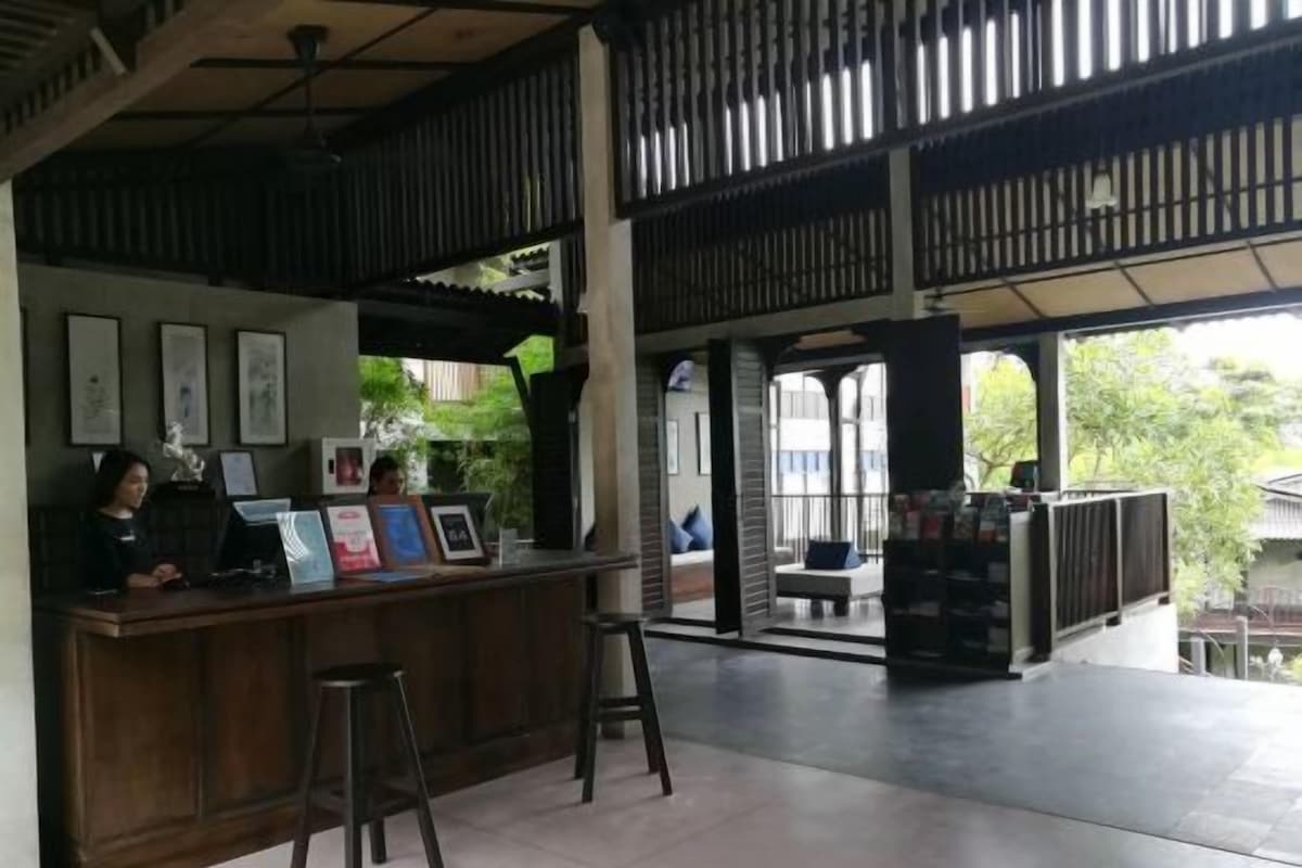 A reception area with a wooden counter, two stools, and framed pictures on the wall.