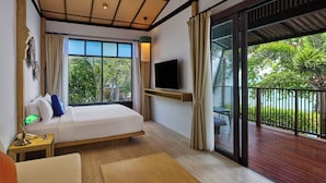 A modern hotel room with a bed, TV, and balcony with a view of greenery. - Homm Chura Samui (Koh Samui)