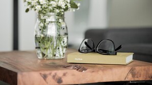 A wooden table with a vase of flowers, a pair of glasses, and a book titled "Pay Book". - Space 59 Ratchaburi (Ratchaburi)