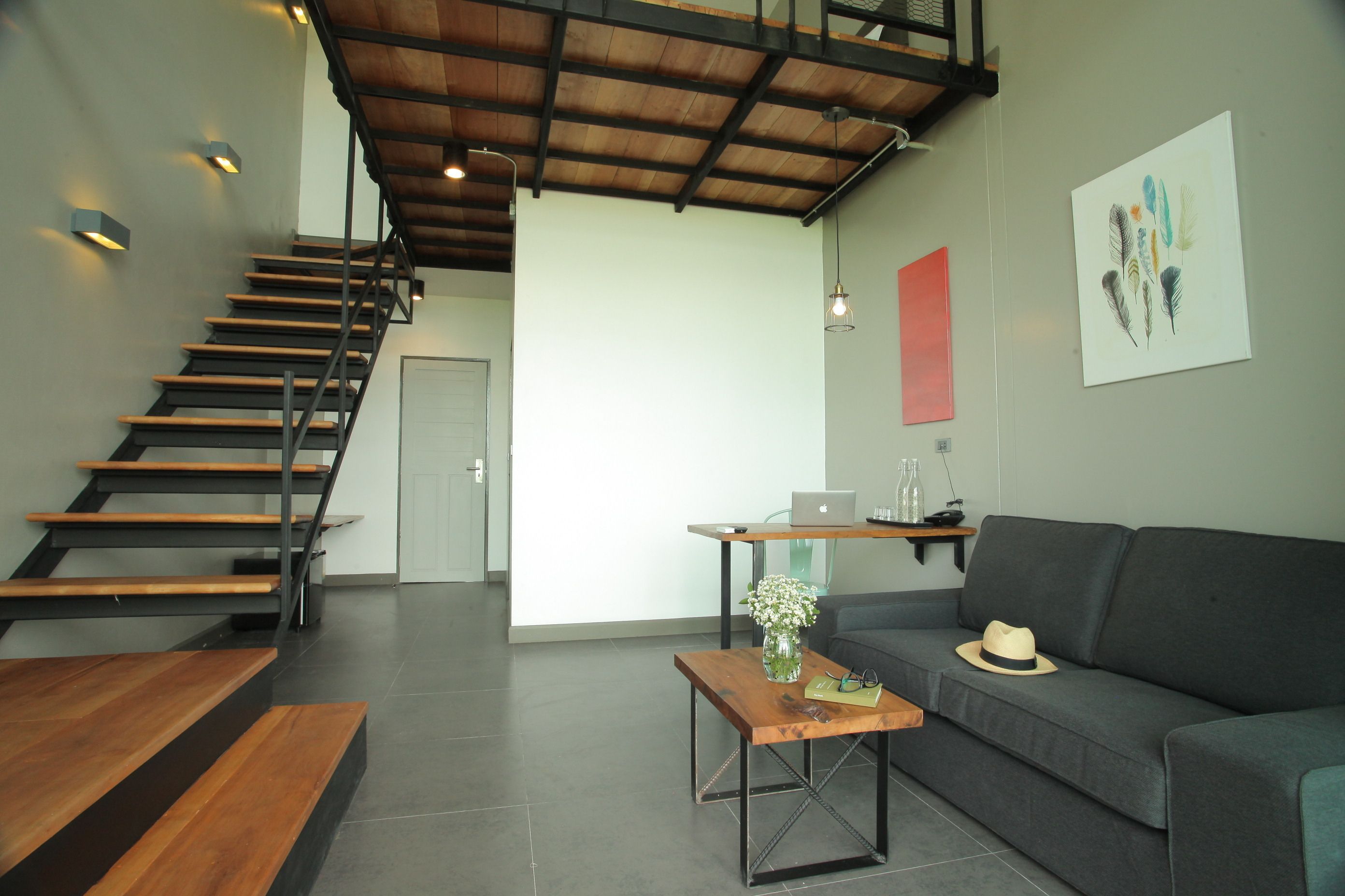 Un intérieur moderne avec un escalier, un canapé, une table basse et un ordinateur portable posé sur un bureau.