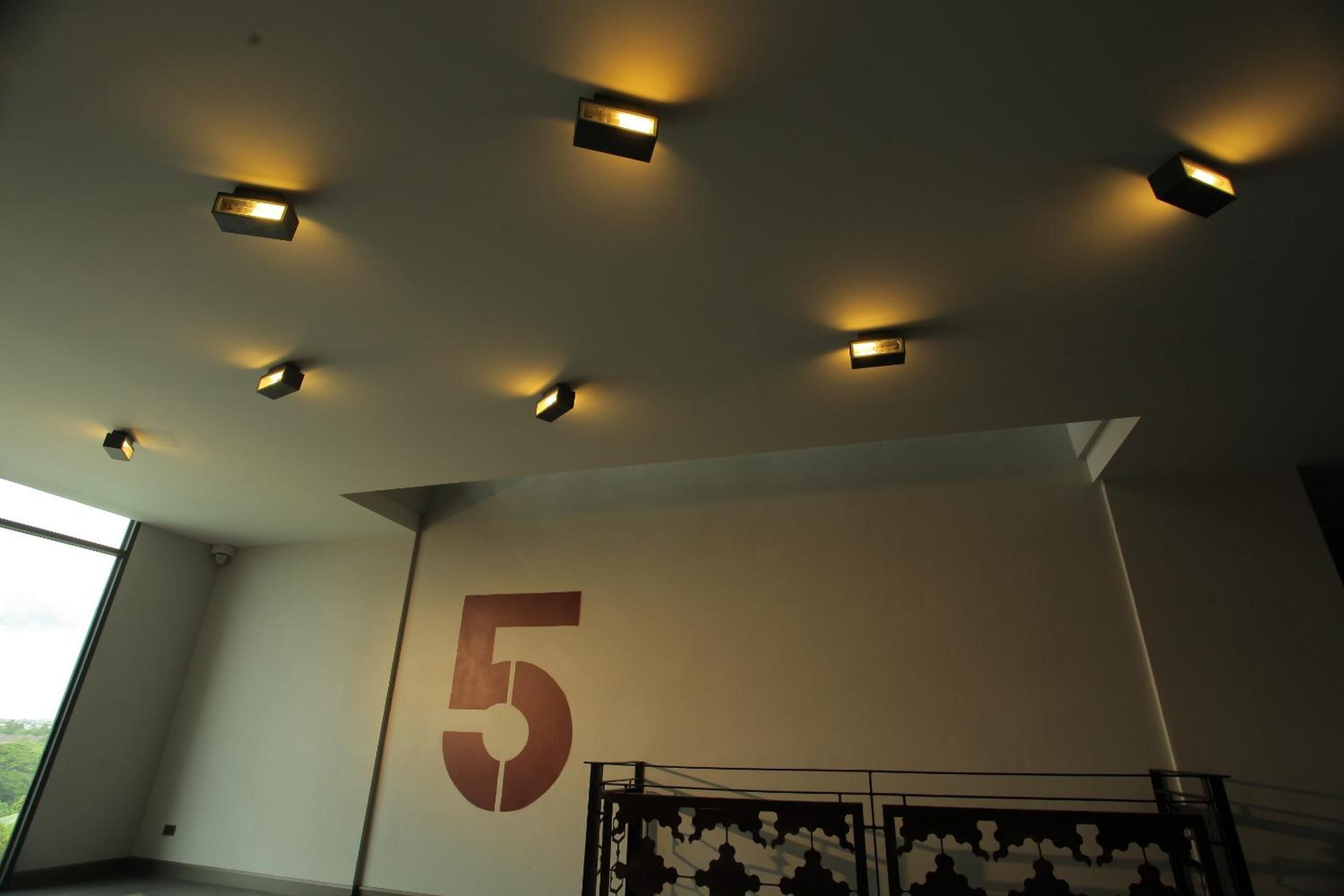 Een modern interieur met inbouwspots, een groot muurgetal '5' en een geometrisch metalen scheidingswand.