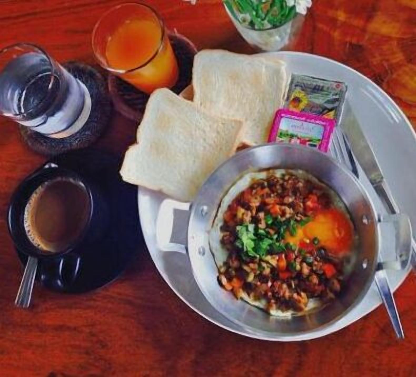 A breakfast setting with toast, a bowl of scrambled eggs with vegetables, a glass of orange juice, and a cup of coffee.