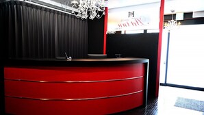 A reception desk with a red and black color scheme, a chandelier, and a sign in the background. - Hotel Art Inn Namba (Osaka)