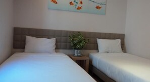 Two single beds with white linens, a headboard, and a small potted plant on a nightstand. - GM City Hotel (Klang)