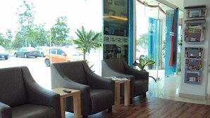A modern interior with two leather armchairs and a small wooden table, a glass door leading outside, and a wall with a display shelf. - GM City Hotel (Klang)