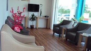 A modern living room with a sofa, two armchairs, a TV, and a potted plant. - GM City Hotel (Klang)
