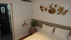 A hotel room with a bed, a small table with a plant, a towel rack, and a wall-mounted air conditioning unit. - GM City Hotel (Klang)