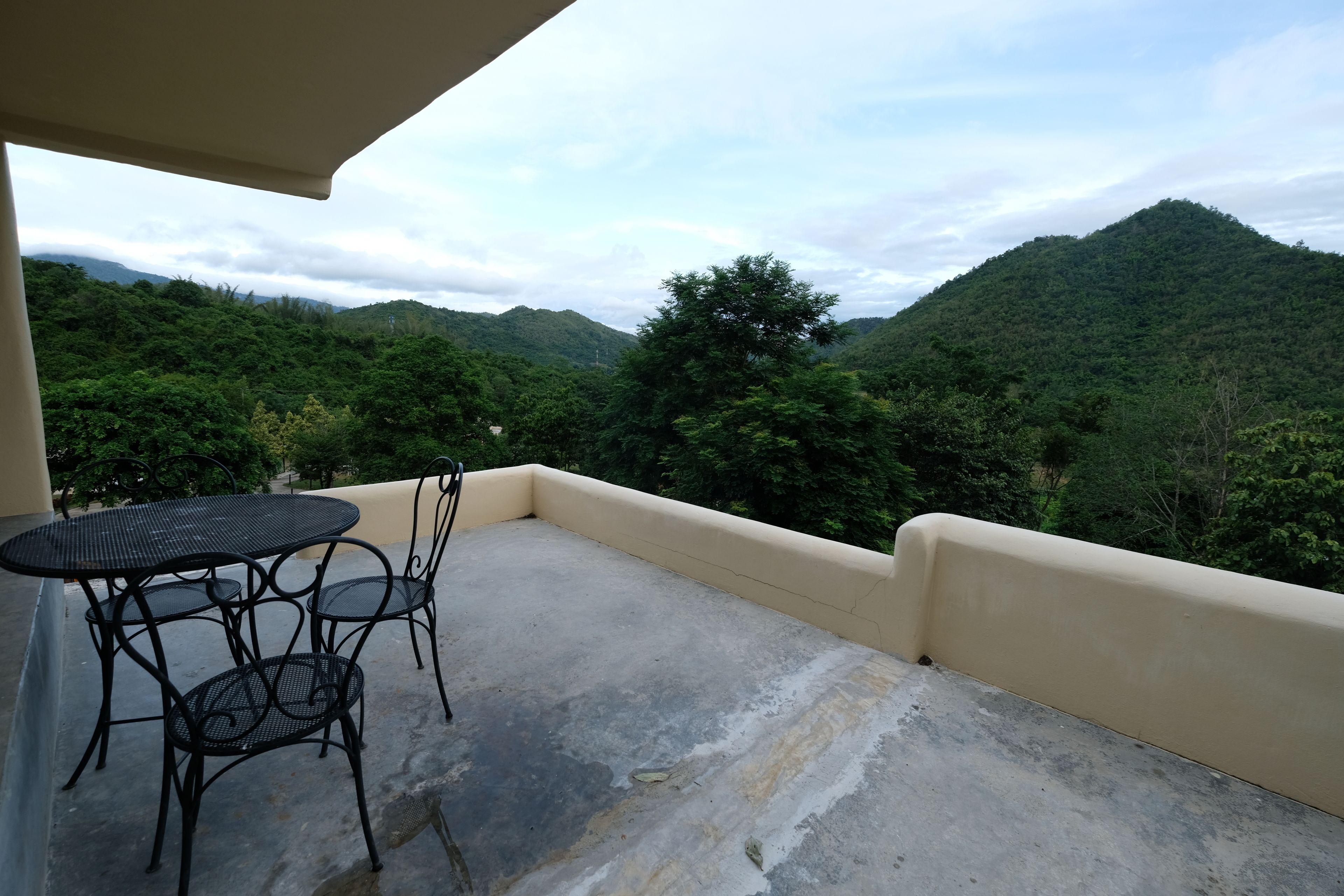 Un balcón con mesa y sillas, con vistas a un paisaje montañoso.