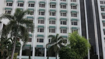 Un hotel con piscina, palmeras y un edificio alto con muchas ventanas.