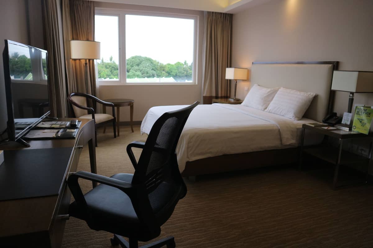 Een hotelkamer met een bed, bureau, stoel en twee bedlampen.