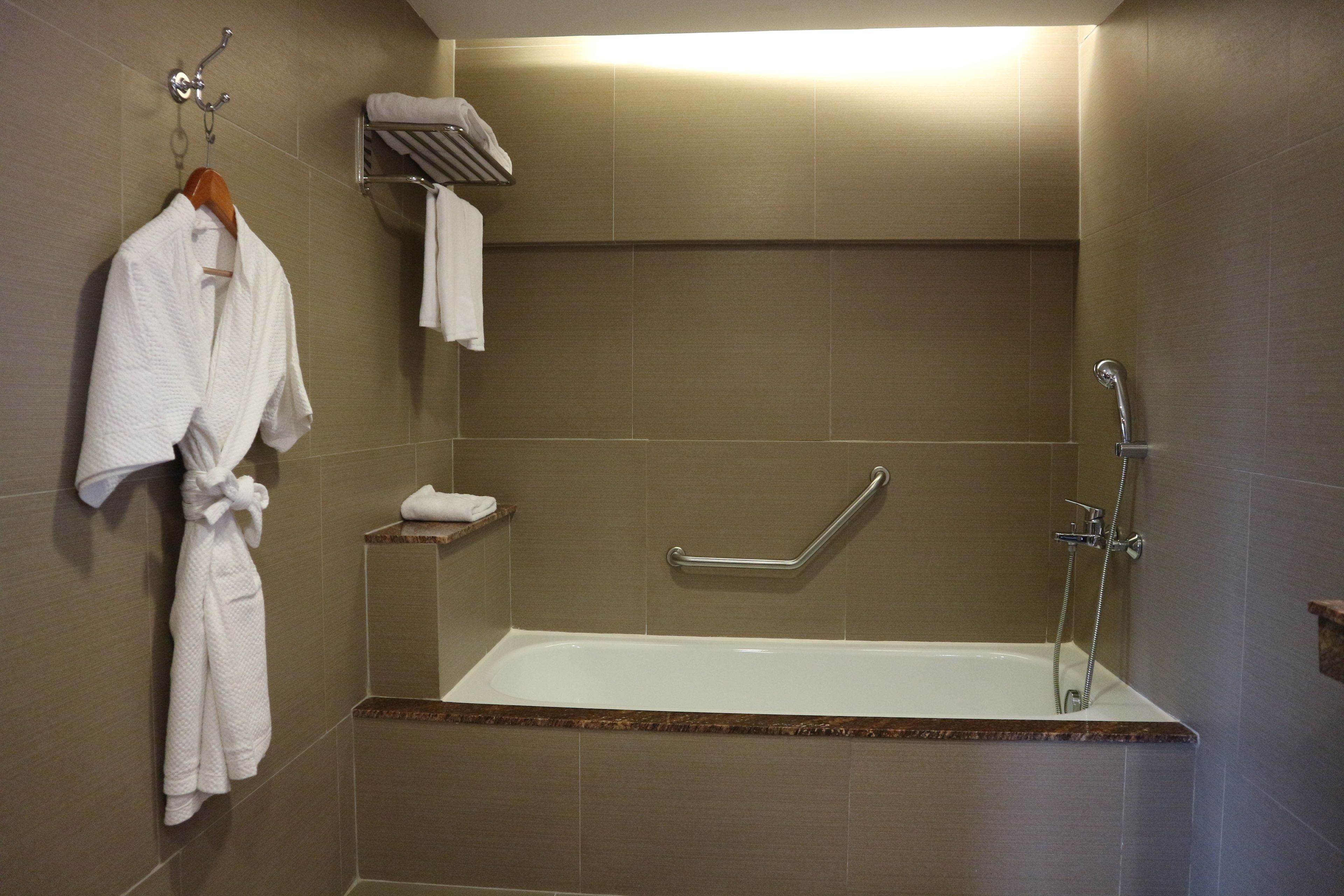 Une salle de bain moderne avec une baignoire, un porte-serviettes et une barre d’appui.