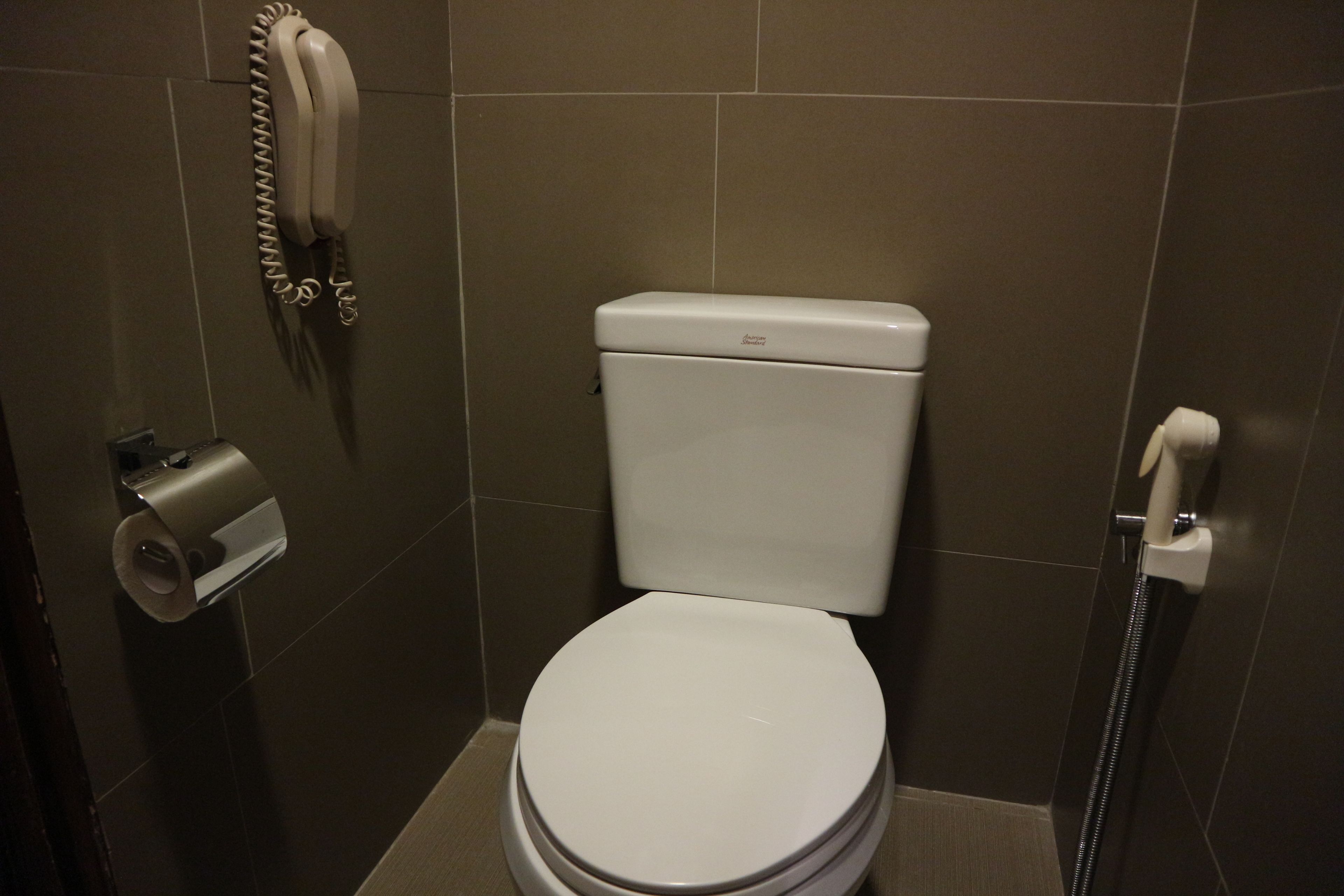 A bathroom with a toilet, a paper towel dispenser, and a hand dryer.
