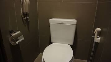 A bathroom with a toilet, a paper towel dispenser, and a hand dryer.