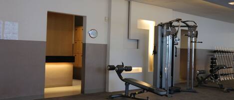 A gym with exercise equipment, a bench, and a wall-mounted clock.