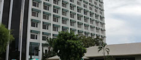 A hotel with a swimming pool, lounge chairs, and a garden area.