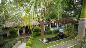 A courtyard with a swimming pool, palm trees, and a tiled-roofed building. - Fort Edge Retreat (Unawatuna)