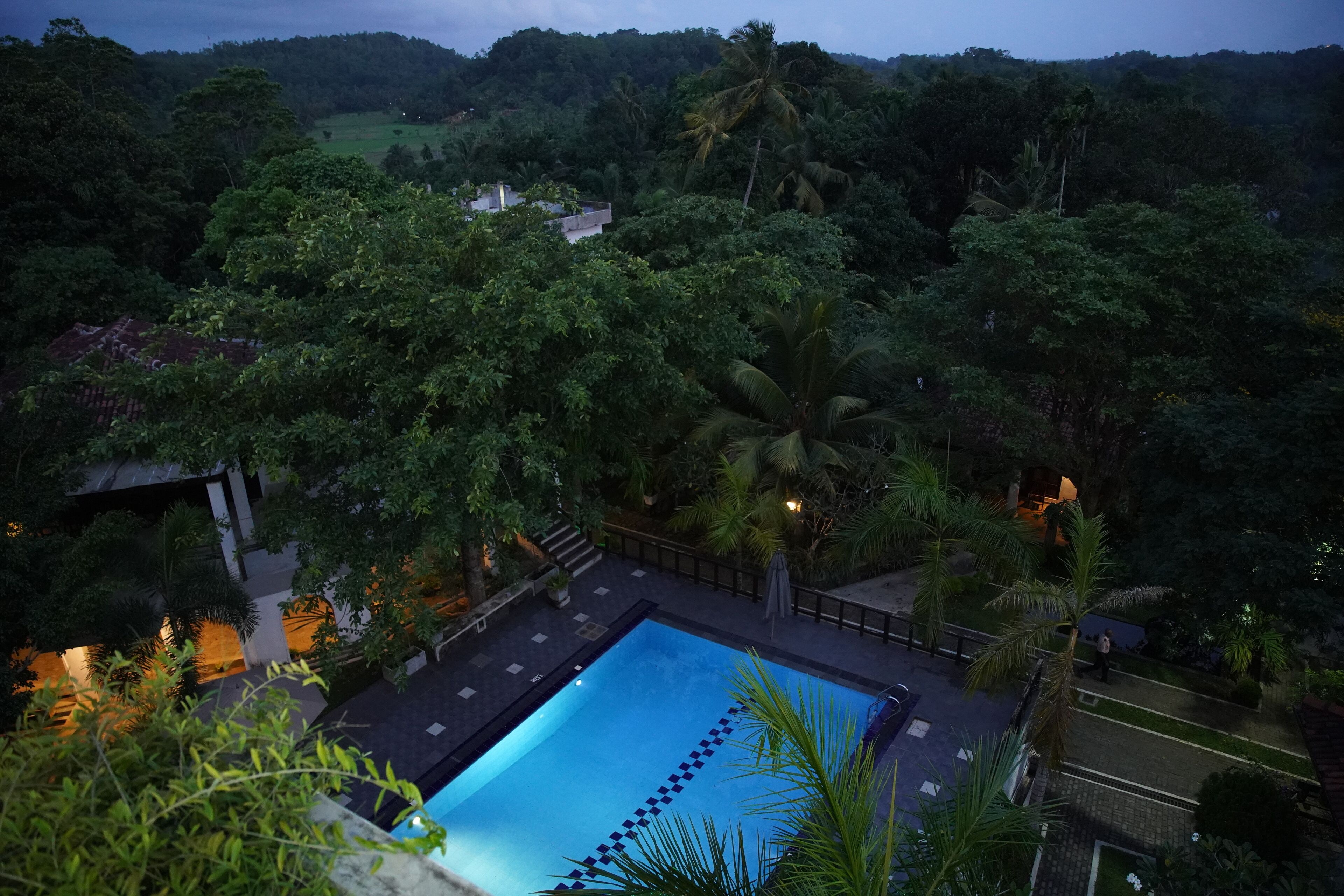A swimming pool surrounded by lush greenery and a view of a hilly landscape.