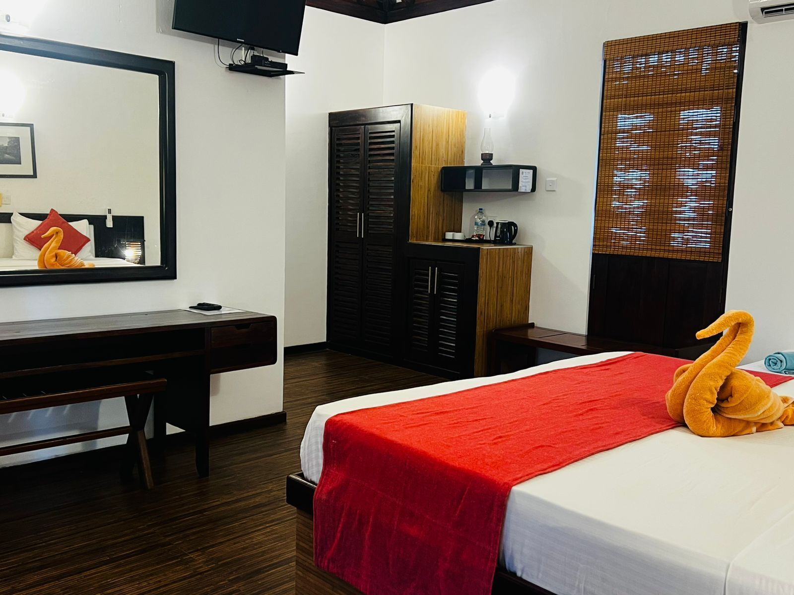 A hotel room with a bed, a desk, a wardrobe, and a television.