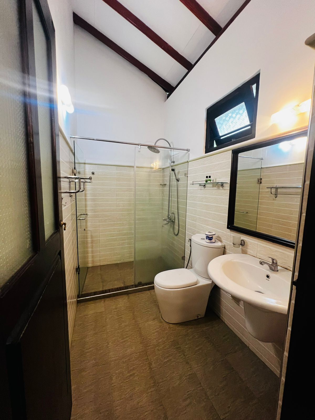A modern bathroom with a glass-enclosed shower, a toilet, and a sink.