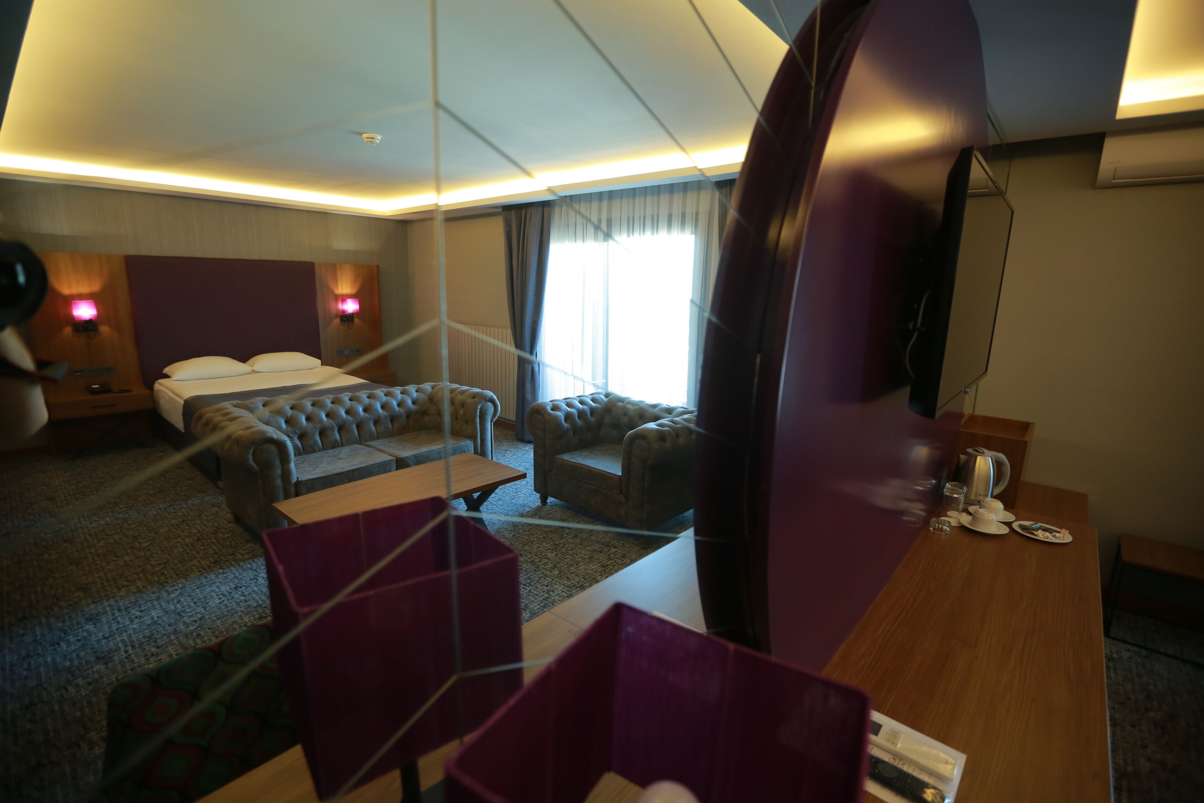 Una habitación de hotel con cama, sofá, escritorio y televisor.