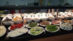 Un bufé con diversas opciones de comida, incluyendo frutas, verduras y postres.