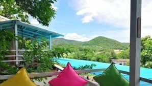A balcony with a view of a turquoise pool and green hills. - Ingmhok Country Mountain View Resort (Suan Phueng)