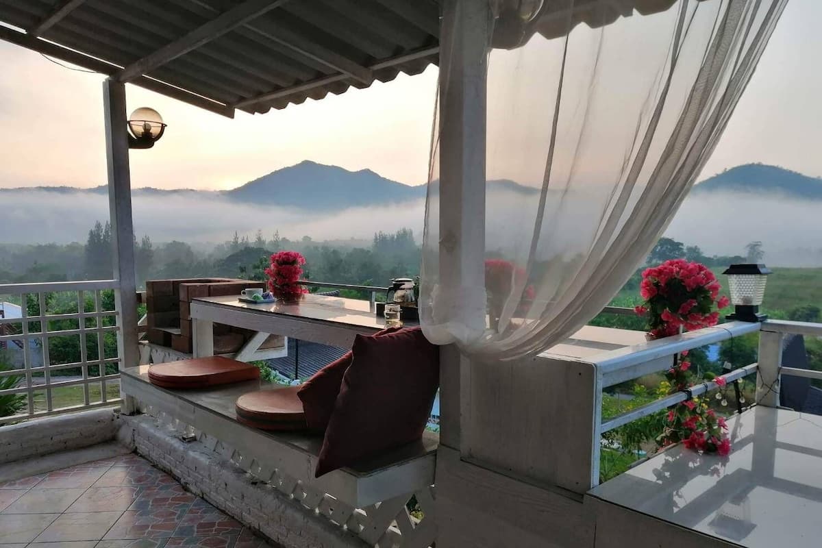 A covered outdoor seating area with a table, chairs, and a view of mist-covered mountains.