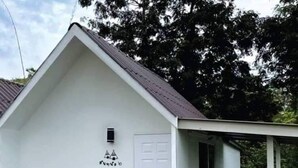 A white building with a sloped roof, a door, and a small porch with potted plants. - Ingmhok Country Mountain View Resort (Suan Phueng)