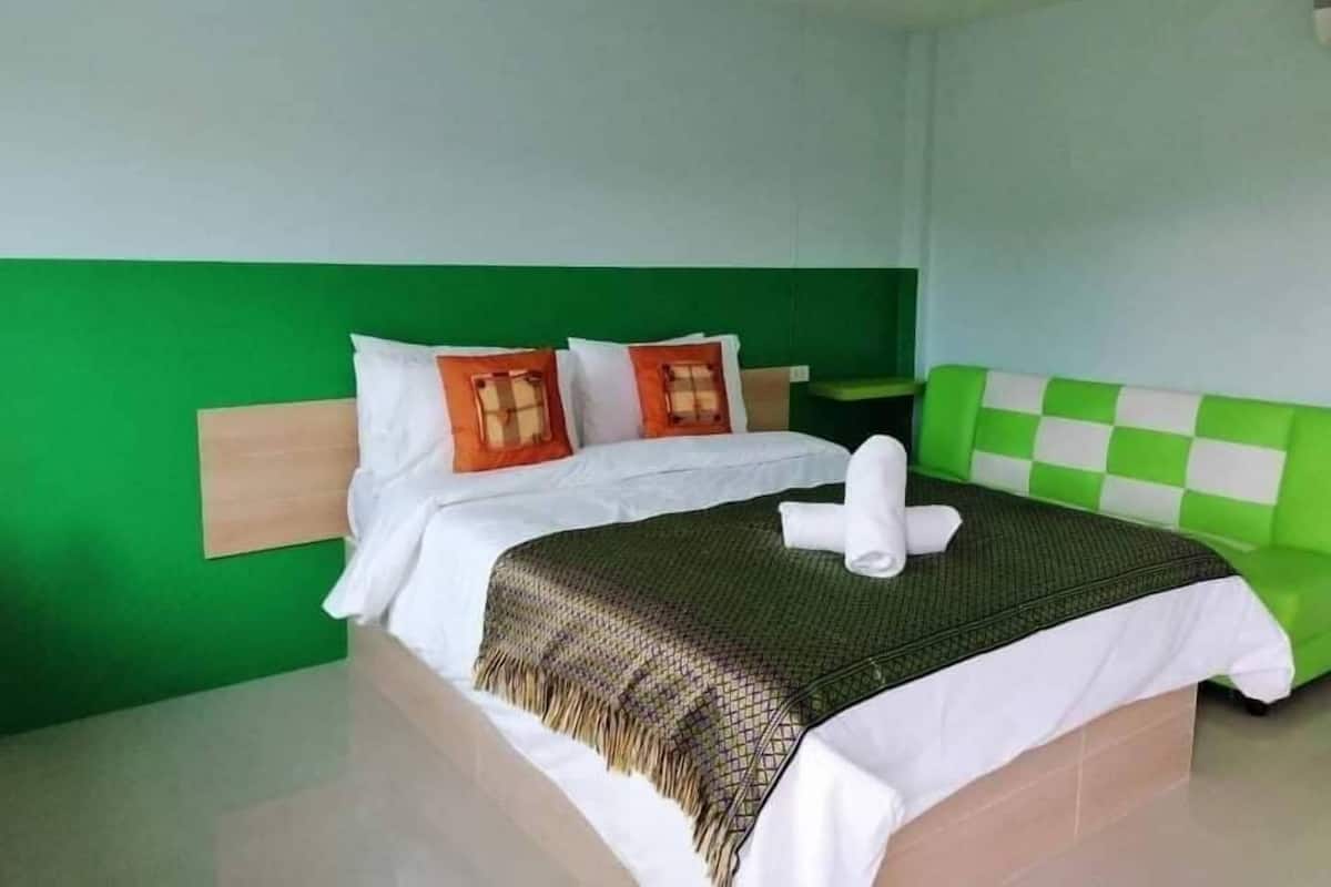 A hotel room with a bed, green walls, and a checkered headboard.