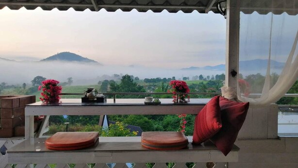 A balcony with a view of a misty landscape and mountains. - Ingmhok Country Mountain View Resort (Suan Phueng)
