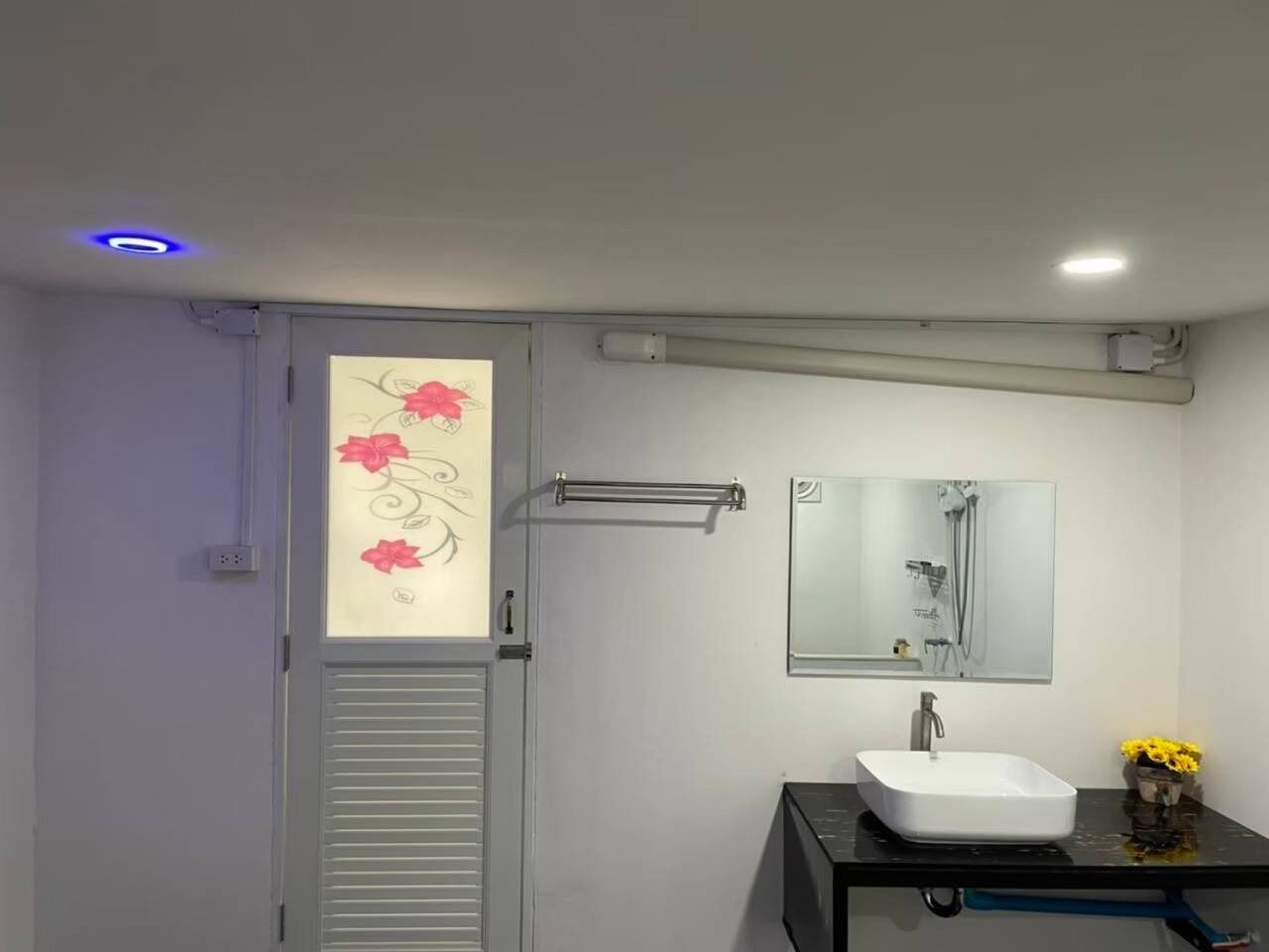 A modern bathroom with a white sink, a mirror, and a towel rack.