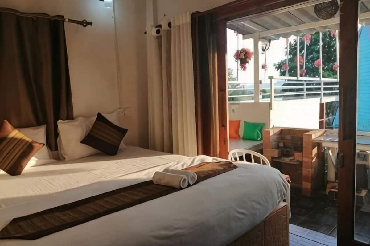 A room with a bed, pillows, a window, and a view of the outside.