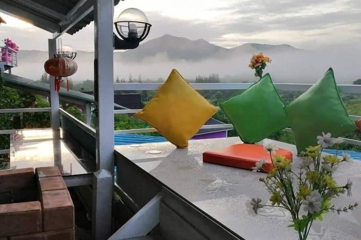 A terrace with a view of mountains, a water feature, and a flower arrangement.
