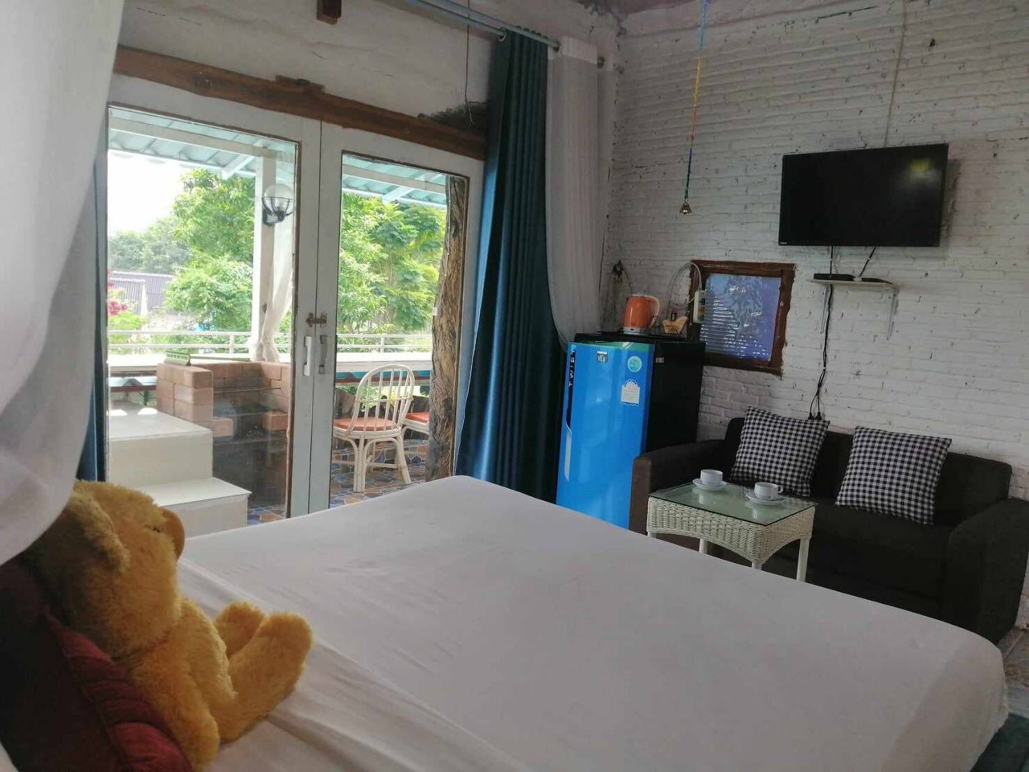 Ett hotellrum med en säng, en tv, ett kylskåp och utsikt över omgivningarna.