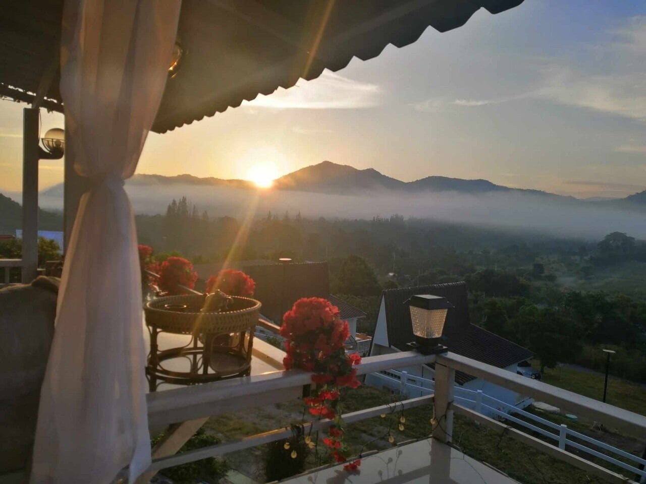 A balcony with a view of mountains and a sunset.