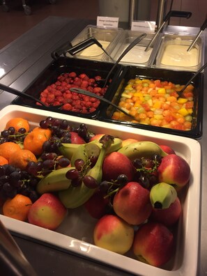 A buffet with various fruits and dips, including strawberries, grapes, and bananas.