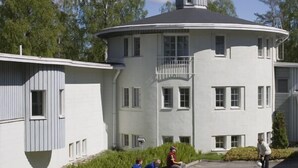 Un edificio grande y blanco, circular, con un balcón y varias ventanas.