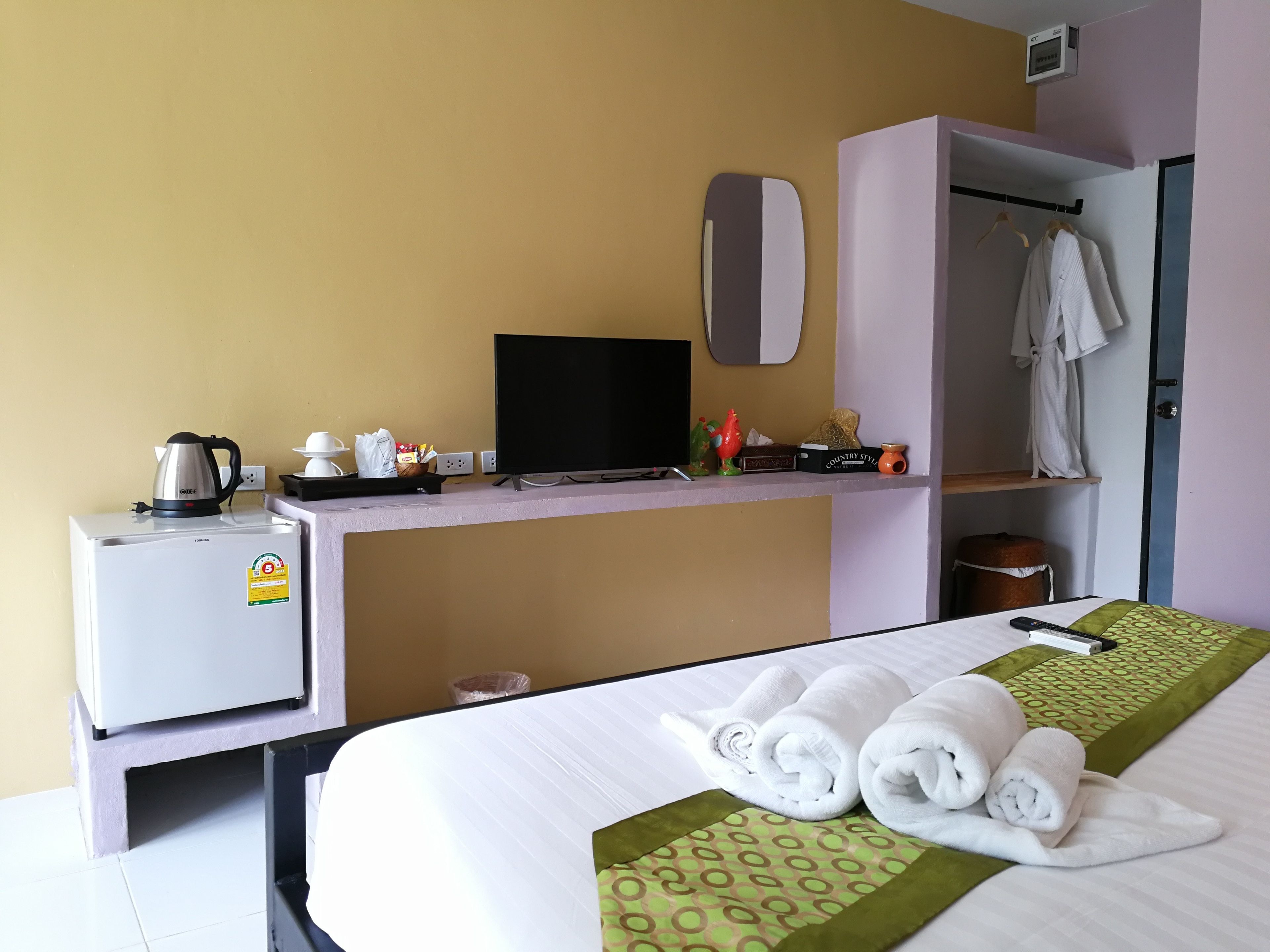 A hotel room with a bed, a desk with a kettle, a TV, and a wardrobe.