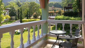 A balcony with a white balustrade, a round table, and two wicker chairs. - Stamp Hills Resort & Restaurant (Suan Phueng)