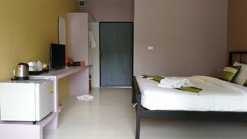 Habitación de hotel con una cama, un escritorio con hervidor, televisión y armario.